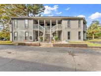 Two-story condo building with exterior stairs, gray siding, and tasteful landscaping at 863 Tall Oaks Ct. # D, Myrtle Beach, SC 29588