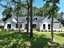 Stunning two-story home with a modern farmhouse design, complemented by lush landscaping and mature trees at 974 Crooked Oak Dr., Pawleys Island, SC 29585
