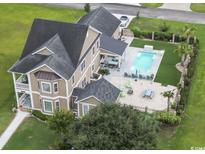 Stunning aerial view of a tan home with a pool, lounge area and well maintained lawn at 712 Crystal Water Way, Myrtle Beach, SC 29579