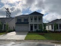 Charming two-story home features a welcoming front porch, a two-car garage, and well-maintained landscaping at 9738 Indigo Creek Blvd., Murrells Inlet, SC 29576