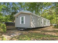 Gray manufactured home with white trim nestled among mature trees on a sunny day at 103 Off Shore Dr., Murrells Inlet, SC 29576