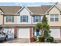 Charming townhome featuring brick accents, a one-car garage, and a blue front door surrounded by mature landscaping at 1098 Stanton Pl., Myrtle Beach, SC 29579