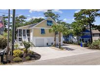 Charming yellow home with blue shutters, a two-car garage, and lush landscaping in a desirable community at 1114 S Dogwood Dr., Surfside Beach, SC 29575