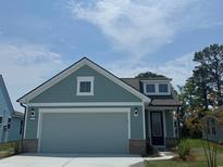 Charming home with a two-car garage, blue siding, brick detail and a manicured lawn at 1233 Lady Bird Way, North Myrtle Beach, SC 29582