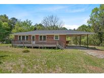 Charming brick home featuring a wooden deck, convenient carport, and lush green surroundings at 2865 N Nichols Hwy., Nichols, SC 29581
