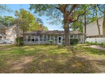 Charming home with a spacious front yard and an enclosed porch featuring many windows for natural light at 634 Melody Ln., Surfside Beach, SC 29575