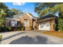 Charming single-Gathering brick home featuring a well-maintained lawn and a spacious driveway leading to a two-car garage at 808 East Coast Ln., North Myrtle Beach, SC 29582