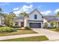 Beautiful white brick home with manicured lawn, dark gray garage door and black pergola at 8418 Cape Dutch Loop, Myrtle Beach, SC 29572