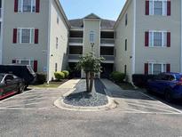 Condominium exterior with parking and central landscaped island with low growing tree at 101 Maddington Place Dr. # 103, Surfside Beach, SC 29575