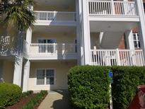 View of the condo's exterior showcasing multiple levels with private balconies and well-maintained landscaping at 1000 Ray Costin Way # 108, Murrells Inlet, SC 29576