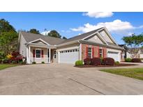 Charming home featuring a well-manicured lawn, brick accents, and a spacious driveway leading to an attached two-car garage at 120 Carolina Crossing Blvd., Little River, SC 29566