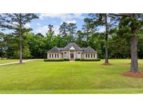 Charming one-story brick home featuring a manicured lawn, lush landscaping, and a symmetrical facade at 4100 Hagwood Circle, Conway, SC 29526