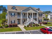 Charming two-story condo with white porch, stairway and well-manicured landscaping at 411 Mahogany Dr. # 202, Murrells Inlet, SC 29576