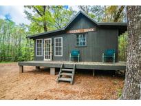 Quaint cabin-style home featuring a front porch with chairs and a charming setting among the trees at 70 Izard Pl., Georgetown, SC 29440