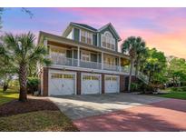 Stunning elevated home boasting a three-car garage, spacious porch, and lush landscaping at 9 Gasparilla Circle, Murrells Inlet, SC 29576