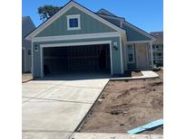 Charming home with teal siding, white trim, open garage, and a freshly poured concrete driveway at 1213 Lady Bird Way, North Myrtle Beach, SC 29582