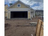 A yellow single Gathering home boasts an open garage with a spacious interior under a cloudy sky at 1213 Lady Bird Way, North Myrtle Beach, SC 29582