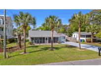 Charming single-story home featuring a metal roof, palm trees, and a well-maintained lawn at 319 Sparrow Dr., Surfside Beach, SC 29575