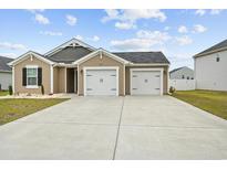 Charming home featuring a two-car garage, well-manicured lawn, and inviting facade with a blue sky backdrop at 115 Foxford Dr., Conway, SC 29526
