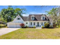 Charming home with a white exterior, dormers, lush landscaping, and attached garage at 129 Old Cedar Loop, Pawleys Island, SC 29585