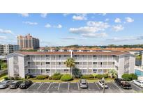 Multi-story condo building with white facade, balconies, parking, and landscaping under a partly cloudy sky at 1919 Spring St. # 36A, North Myrtle Beach, SC 29582
