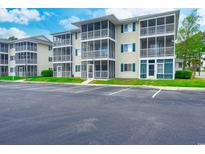 Attractive condominium building with screened porches and ample parking on a sunny day at 202 Landing Rd. # B, North Myrtle Beach, SC 29582