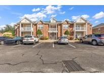 Condominium building with brick facade, multiple balconies, and ample parking on a sunny day at 2037 Silvercrest Dr. # 16E, Myrtle Beach, SC 29579