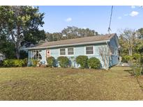 Charming single-story home featuring light blue siding and a well-manicured lawn with mature shrubbery at 210 16Th Ave. N, Surfside Beach, SC 29575