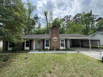 Charming single-story home with a brick chimney, well-manicured lawn, and attached carport at 342 Red Fox Rd., Myrtle Beach, SC 29579