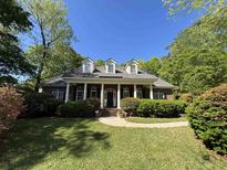 Charming brick home featuring a manicured lawn, dormer windows and a covered front porch with elegant columns at 4535 Carriage Run Circle, Murrells Inlet, SC 29576