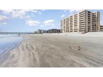 Expansive beach view with a fishing pier and condo buildings in the background on a sunny day with puffy clouds at 6100 N Ocean Blvd. # 804, North Myrtle Beach, SC 29582