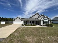 Charming single-story home with a manicured lawn and inviting front porch with rocking chairs at 7370 Johnson Shortcut Rd., Conway, SC 29527