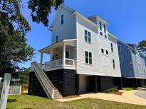 Stunning exterior of a raised beach home with a covered porch and stairs leading to the main level at 108 Tidal Creek Dr., Garden City Beach, SC 29576