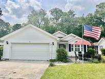 Charming single-story home with a well-manicured lawn and an inviting front patio area with seating at 1516 Saint George Ln., Myrtle Beach, SC 29588