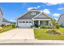 Charming single-Gathering home with a well-manicured front lawn, flower bed, and inviting front porch at 296 Switchgrass Loop, Little River, SC 29566