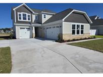 Charming two-story home with a three-car garage and manicured front lawn on a sunny day at 1004 Gold Dew Way, Myrtle Beach, SC 29579