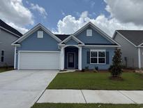 Charming one-story home with a blue exterior, a well-manicured lawn, and an attached two-car garage at 4027 Bucolic Loop, Myrtle Beach, SC 29588