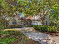 Beautiful exterior with a long driveway and attached garage nestled among mature trees and landscaping at 710 Masters Dr., Pawleys Island, SC 29585