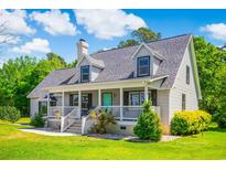 Charming home featuring a welcoming front porch, well-manicured lawn, and gray siding at 2400 Bay View Dr., Green Sea, SC 29545
