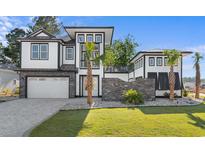 Beautifully designed modern home with a stone facade, manicured lawn, and a two-car garage at 100 Serenity Point Dr., Little River, SC 29566