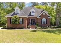 Charming brick home featuring a well-manicured lawn and inviting front porch and a beautiful garden at 124 Windmeadows Dr., Conway, SC 29526