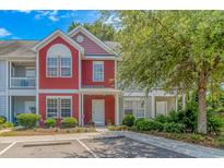 Charming two-story townhome with red siding, manicured landscaping, and inviting front entrance at 1631 Low Country Pl. # E, Myrtle Beach, SC 29577
