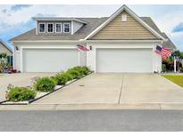 Charming home featuring a spacious two-car garage, adorned with American flags, and a well-maintained front yard at 1856 Melville Ct., Little River, SC 29566