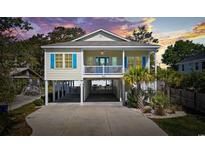 Charming elevated beach home featuring a spacious covered parking area, blue accents, and a cozy front porch at 2602 Holly Dr., North Myrtle Beach, SC 29582