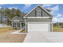 Charming home exterior featuring a two-car garage, landscaped front yard, and green siding at 4010 Macks Rd, Aynor, SC 29511