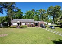 Charming brick home with manicured lawn, attached garage, and long driveway, surrounded by mature trees under a clear blue sky at 408 South Farr Ave., Andrews, SC 29510