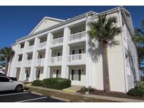 Three-story condo building featuring white siding, columned balconies, and a palm tree in the yard at 5020 Windsor Green Way # 302, Myrtle Beach, SC 29579