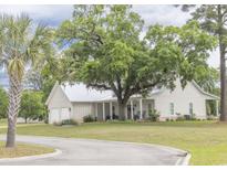 Charming single-story home with a metal roof, rocking chair front porch, and mature landscaping at 521 Oak Lawn Rd., Georgetown, SC 29440