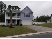 Charming two-story home featuring a spacious driveway and a welcoming front porch with classic railings at 534 Pacific Commons Dr., Surfside Beach, SC 29575