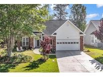 Charming brick home featuring a two-car garage, well-manicured lawn, and inviting front garden at 552 Sand Ridge Rd., Conway, SC 29526